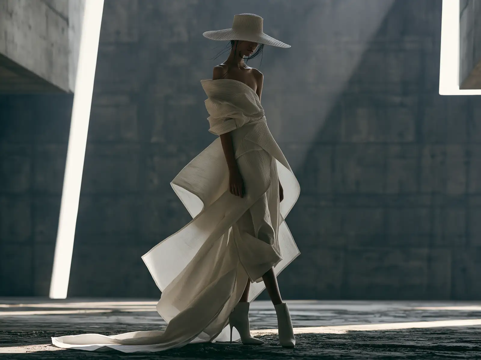 A couture gown and wide hat against concrete